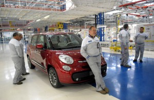 Employees stand next to  a new Fiat 500